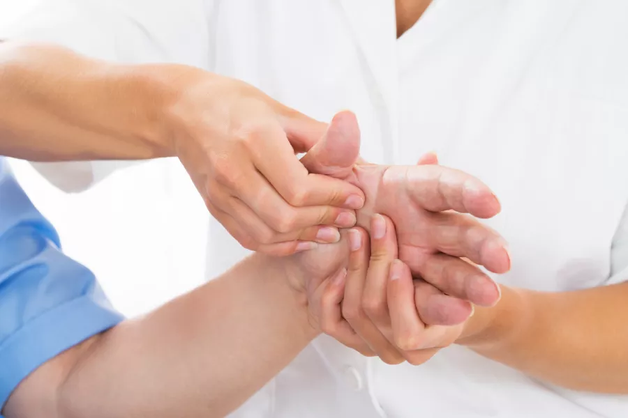 Doctor haciendo fisioterapia reumatológica en una mano